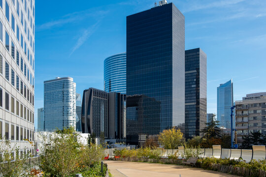Modern corporate office skyscraper architecture shapes the urban financial skyline in Paris La Defense under clear blue sky with city garden