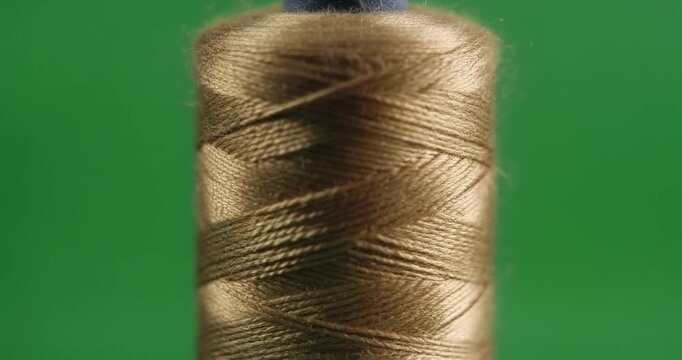 A spool of brown thread on a green screen background close-up shot for textile industry