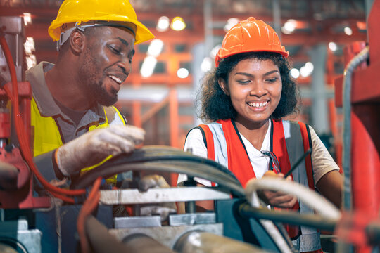 Two happy factory workers team African American man black woman engineer checking machine manufacturing plant Industrial safety helmet heavy industry teamwork production maintenance mechanic gear vest