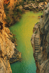 Obraz premium Deep steep cliff with stairs and river running through. Seen from above. Guadalhorce river, Malaga, Andalusia, Spain.