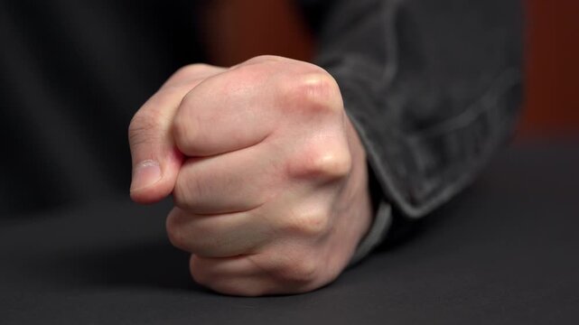 A man's fist hitting the table. Man losing his temper, aggressive man clenching his fist and angrily hitting the table. Outburst of anger. Losing his temper and showing the concept of aggression.