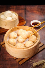 Traditional Chinese Xiao Long Bao Soup Dumplings in Bamboo Steamers with Chopsticks and Sauce