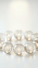 Elegant clear glass spheres with golden glitter sparkles arranged in row on white surface with warm bokeh lights creating festive holiday atmosphere.