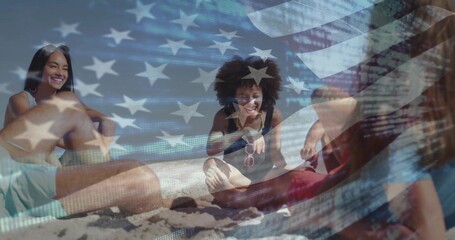 Obraz premium Sitting group in swimsuits chatting on beach, holding pink sunglasses under American flag overlay