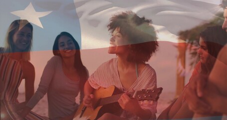 Obraz premium Playing guitarist strumming on sand at beach sunset, flag overlay, palm, wearing summer clothes