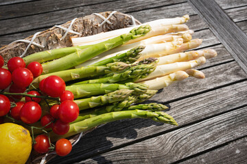 White and green asparagus with cherry tomatoes on gray wood. Background for a healthy nutrion concept. Top view.