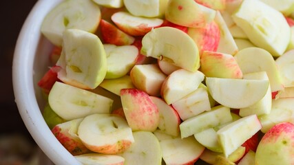 Close-up shot of pieces of cutting organic apples in white bucket.