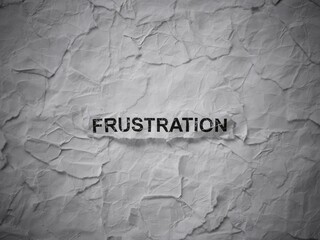 Crumpled piece of paper with word Frustration on torn crumpled white paper pieces background