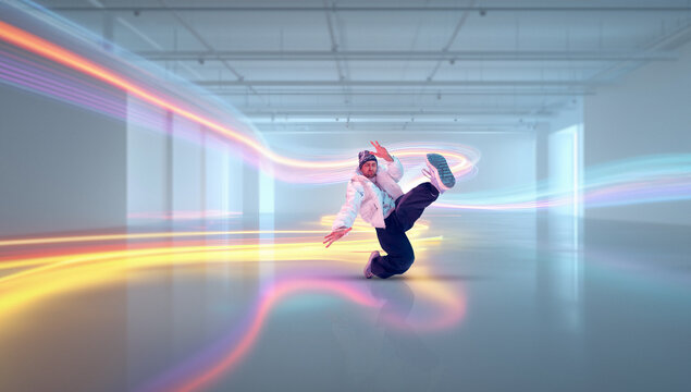Dynamic composition breakdancer kicking with light trails in studio space. Concept of motion visualization, creative dance content, modern visual effects, and commercial media production.