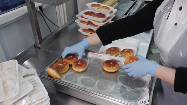 Packaging of ready-made meat pies, belish in containers at food production