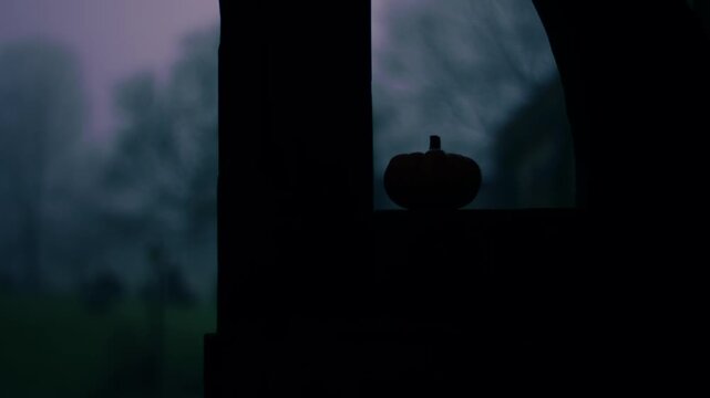 Pumpkin in lonely Graveyard on foggy day though view of lych gate