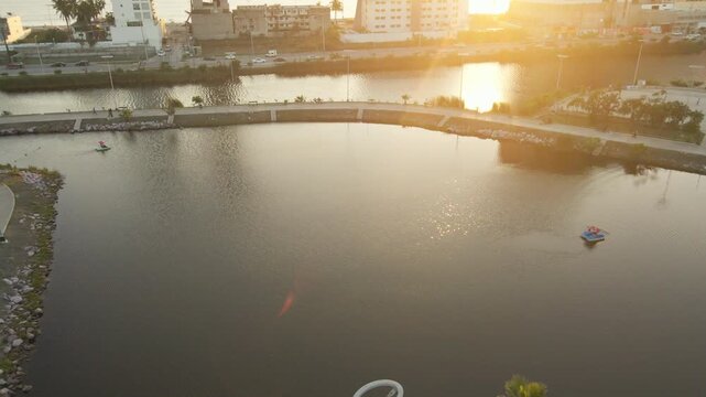 Top down aerial view of the central park lake in Mazatlan, sunset water reflections and golden hour ripples.