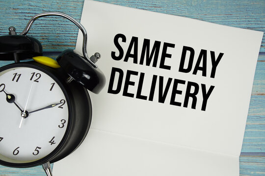 Notepad on a blue wooden table with the words "Same Day Delivery" and alarm clock