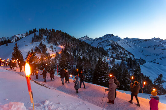 Austria, Tirol, Tannheimer Tal, Neunerkoepfle, winter hike during sunset with torch
