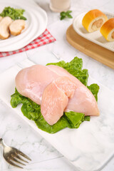 Raw Chicken Breast Fillets on Lettuce Leaves Ready for Cooking on Marble Counter