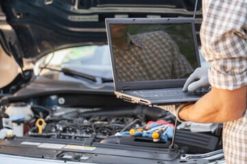 Mechanic uses a laptop to record error engine checks