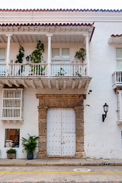 Colonial house in downtown Cartagena featuring whitewashed walls, coral stone doorway, wooden balcony and clay tile roof typical of Caribbean construction