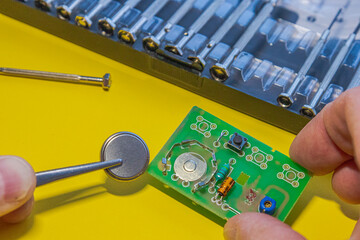Hands holding circuit board and coin battery © JackCA