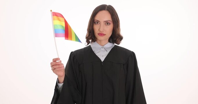 Serious judge woman in robe holds rainbow flag waving. Law supporter raises finger while firmly warning crowd about respect for LGBT equality rights