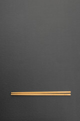 Wooden chopsticks on dark textured background with copy space
