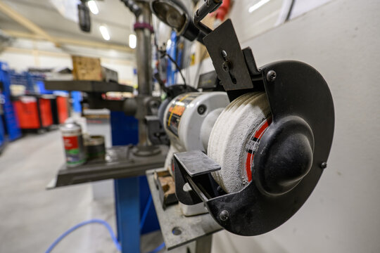 Ground grooves in a white wheel on a bench grinder in the workshop.