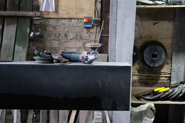 Tools are arranged on a black surface in a workshop setting with various items around