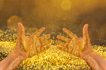 Hands catch golden particles in the bright light.