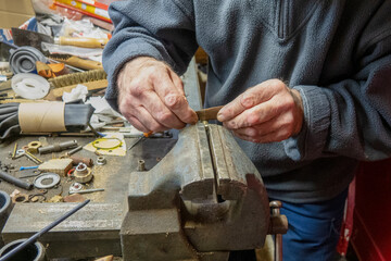 A person shapes metal using tools in a workshop