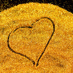 A heart shape is drawn in golden sand with care