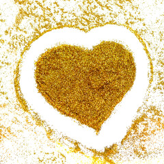 Heart-shaped gold powder on white background