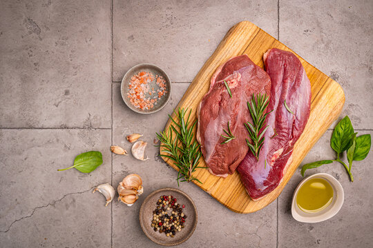 Preparation for cooking raw duck breast with ingredients on dark background, top view. Space for text. High quality photo