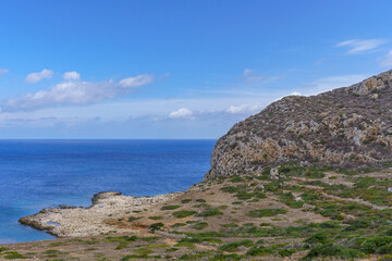Fototapeta premium A picturesque view of Puntazza A Carcara, a beautiful, secluded cove on Levanzo Island, featuring vibrant turquoise and deep blue Mediterranean water gently meeting a rocky beach, ideal for themes of 