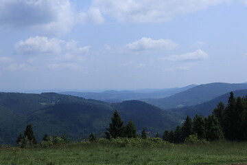 Mountain landscape with forested hills and blue sky
