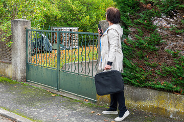 Woman waits at a gate while holding a phone and bag