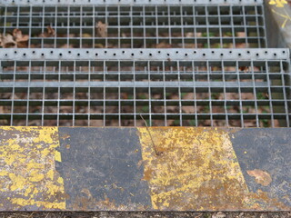 Black and yellow warning markings in front of a walkway grating