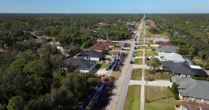 Temporary traffic lights and cones mark closed lane on Florida street under construction, with workers and vehicles near private driveways.