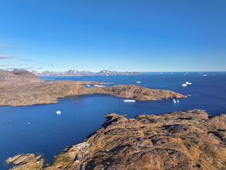 View of the waterfront infrastructure in Tasiilaq, Greenland. The clip shows the port area with shipping containers, fishing boats, and local housing, highlighting life in a remote Arctic community 