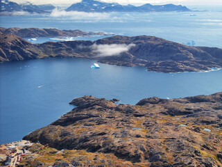 View of the waterfront infrastructure in Tasiilaq, Greenland. The clip shows the port area with shipping containers, fishing boats, and local housing, highlighting life in a remote Arctic community 