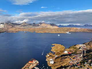 View of the waterfront infrastructure in Tasiilaq, Greenland. The clip shows the port area with shipping containers, fishing boats, and local housing, highlighting life in a remote Arctic community 