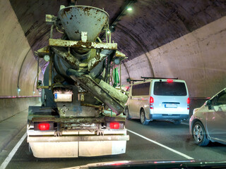 Traffic jam in tunnel with concrete mixer, vans and cars under artificial lighting in Malta. Representation of urban mobility in daily island life