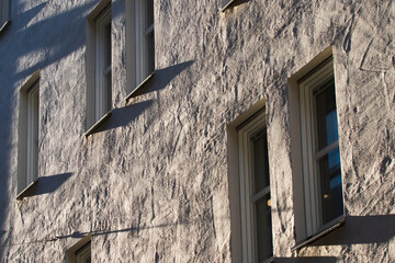 Textured Building Facade With Windows and Sunlight Shadows