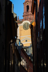 Church Clock Tower Seen Through Narrow Old Town Alley at Sunset