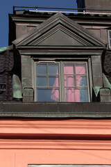 Dormer Window on Historic Building With Copper Roof and Pink Curtain