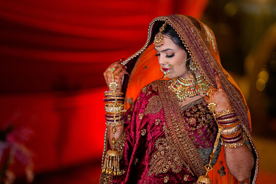 Indian wedding bride wearing embroidered lehenga, heavy gold jewelry, veil, and mehndi hands, representing luxury bridal fashion, traditional ceremony, and premium wedding aesthetics.