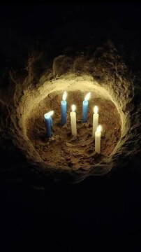 A high angle close up shot video of a hole dug in the beach sand filled with burning candles during the iemanja celebration
