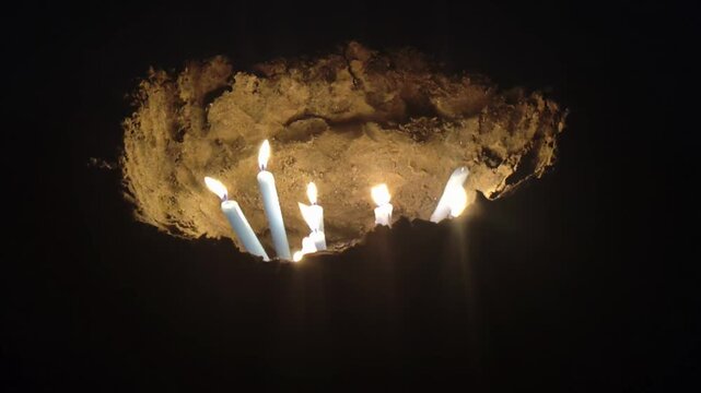 A high angle close up shot video of a hole dug in the beach sand filled with burning candles during the iemanja celebration