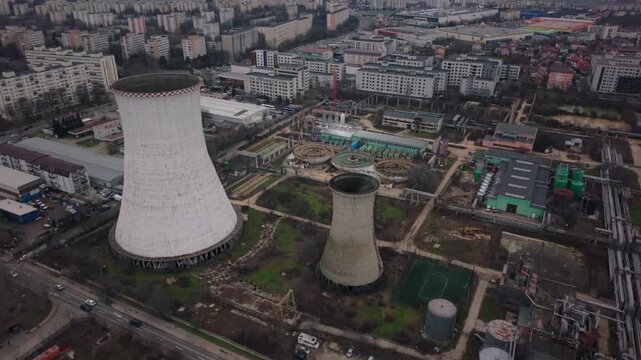 Aerial drone footage of a thermal power plant cooling tower and chimney in Bucharest, Romania.