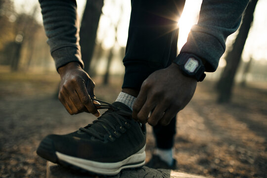 Male runner tying shoelaces in park at sunrise