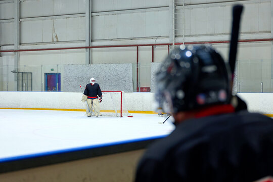 A hockey player attacks an opponent's goalkeeper
