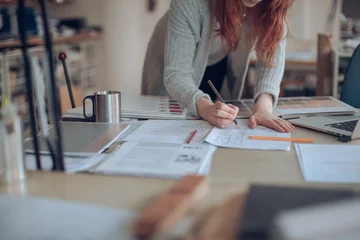 Fotobehang Restaurant Female architect sketching blueprints at office desk  © Geber86